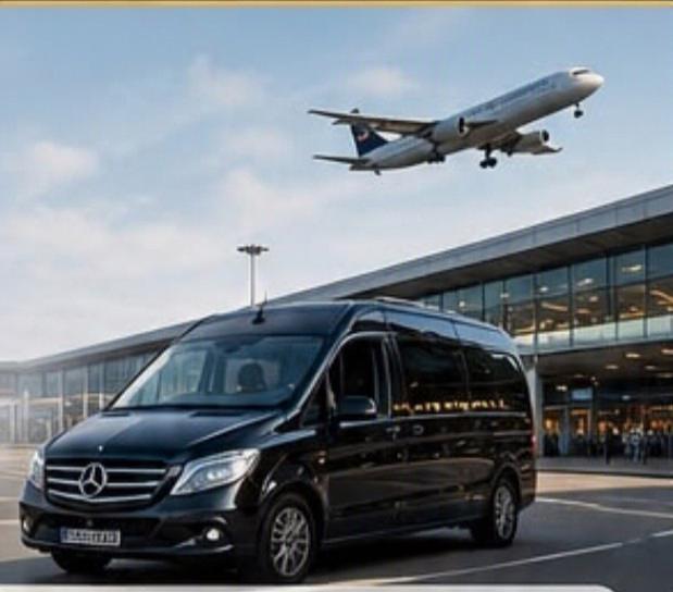 Black Mercedes-Benz minibus waiting outside an airport terminal as an aircraft takes off overhead