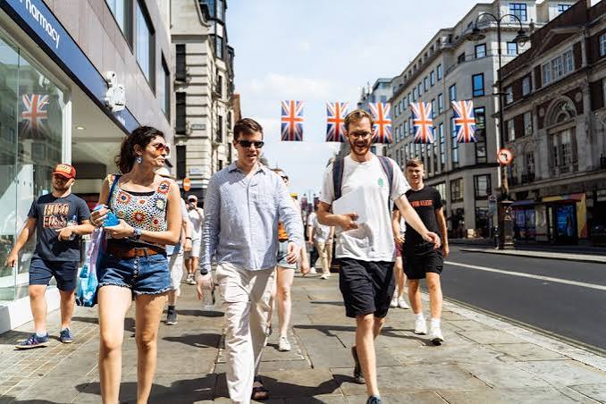 Walking tour group strolling along a London street with Union Jack bunting overhead